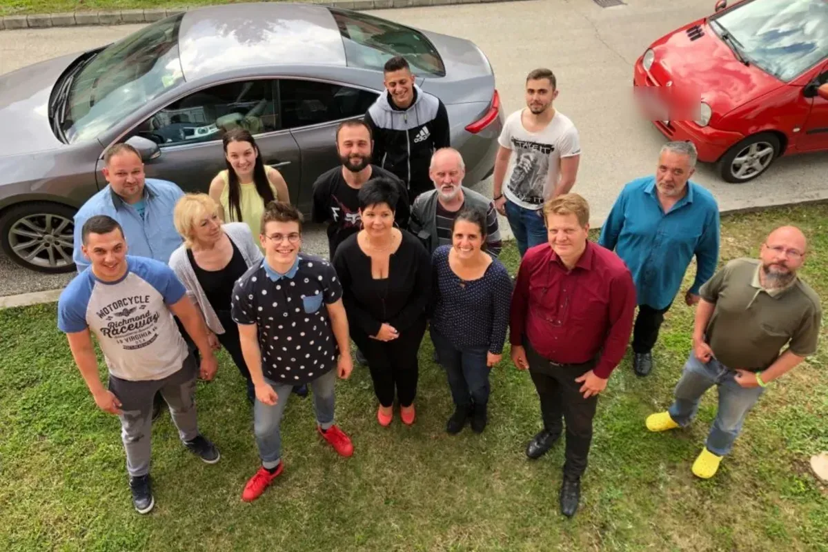 Az ÖkoTech-Home munkatársai csoportképen egy füves udvaron, felülről fotózva; mögöttük parkoló autók